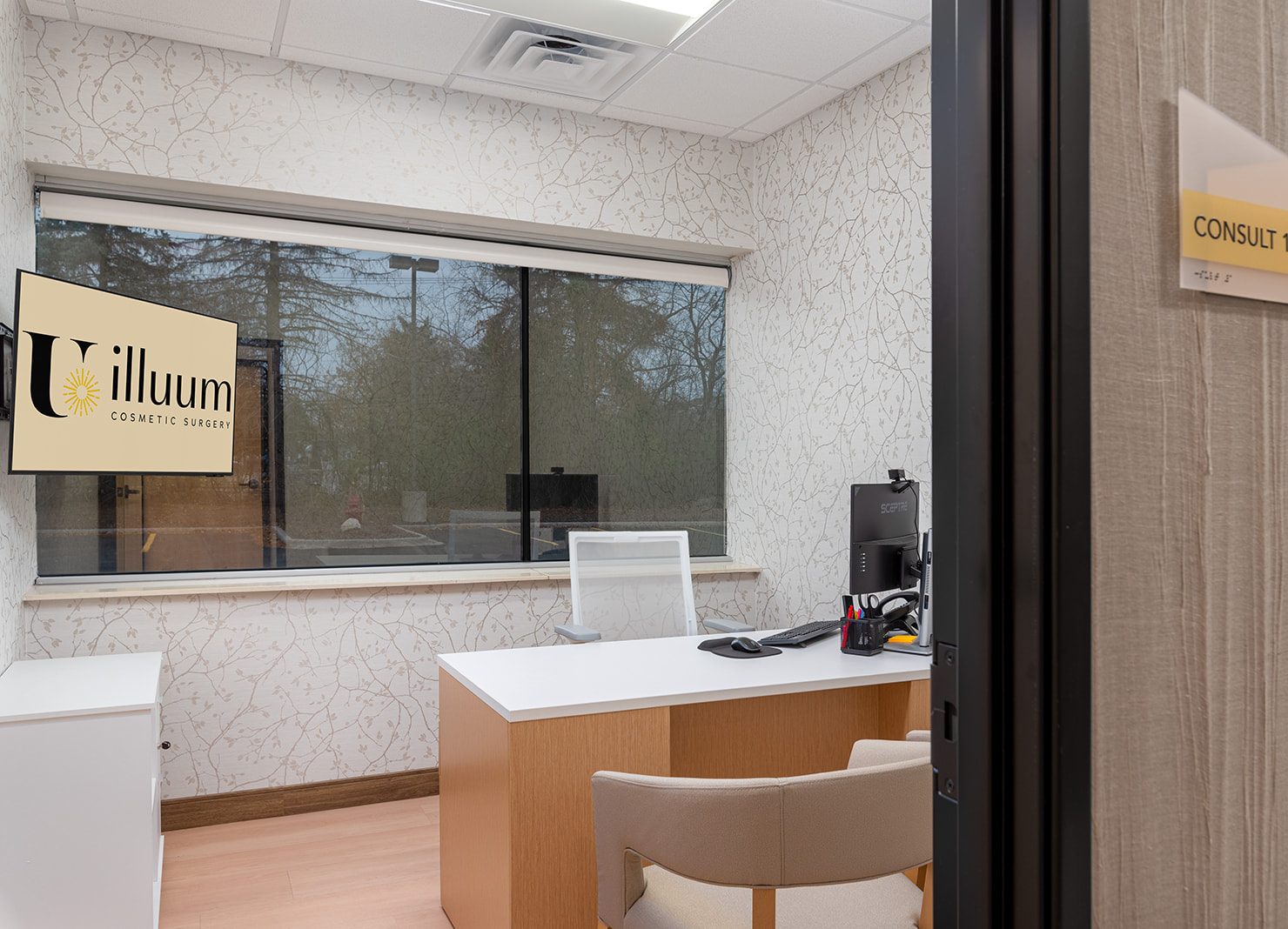Illuum Cosmetic Surgery consultation room with reception desk, window view, and Consult 1 door sign